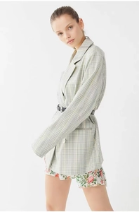 Detail of light green plaid blazer featuring a notched lapel and black waist belt