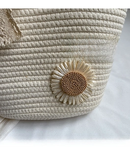 Close-up of beige hand-woven tote bag featuring a large decorative woven flower detail