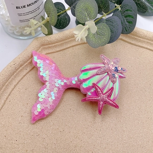Detail of pink mermaid tail hair clip with shimmering sequins, starfish and shell accents