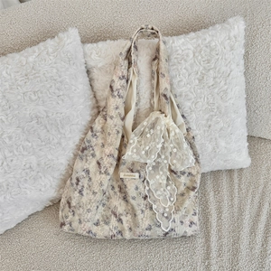 Detailed shot of beige canvas tote bag featuring purple floral patterns and lace bow