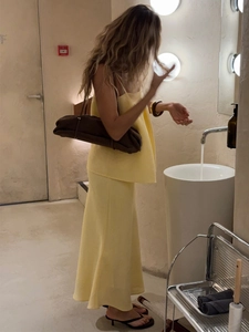 Detailed texture of light yellow satin camisole and fishtail skirt set for women