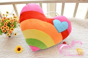 Close-up of rainbow heart plush pillow with colorful stripes and soft heart applique