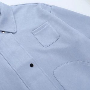 Detail of light blue faux suede jacket showing texture with dark metal snap buttons and pocket