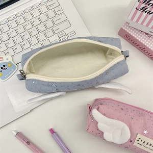 Detail of fabric pencil cases featuring plush angel wings and shiny star patterns