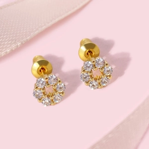 Macro detail of gold plated flower stud earrings with sparkling crystals on silk ribbon