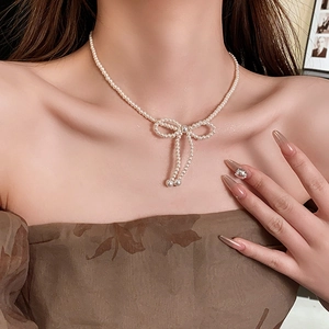Close-up of French bow pearl necklace worn as a collarbone chain on a model