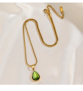 Detailansicht einer goldenen Schlangenkette mit grünem Wassertropfen-Anhänger