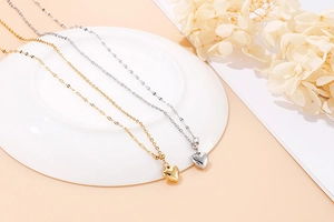 Detailed view of gold and silver heart-shaped pendant necklaces on a white ceramic plate