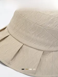 Detail shot of beige sun bucket hat showing pleated texture and premium fabric stitching