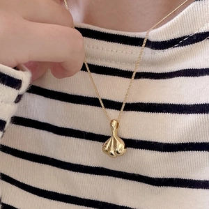 Close-up of a 925 sterling silver gold-plated necklace with a 3D folded pendant on a model