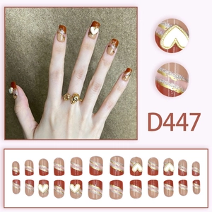 Press-on nail set D447 featuring red-brown heart designs and gold glitter accents