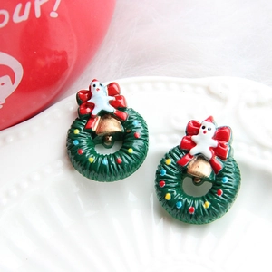Close-up of festive Christmas wreath earrings with red bows and colorful resin ornaments