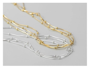 Detail of multi-layer snake bone chain necklaces in gold and silver finishes