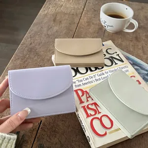 Minimalist accordion card holders in lilac, beige, and mint green on a wooden table