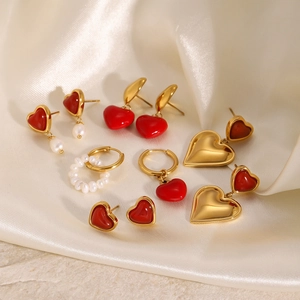 Goldenes Herzohrring-Set mit roter Emaille und weißen Perlen auf Seidenhintergrund