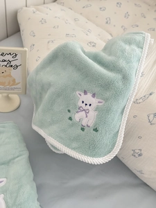 Close-up of soft mint green flannel baby blanket featuring cute lamb embroidery detail