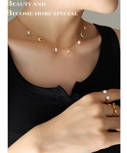 Detalle de collar con borlas de estrella y luna doradas y perla natural de agua dulce