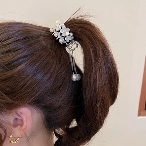 Close-up of silver flower hair claw with white pearls, rhinestones and elegant long tassels