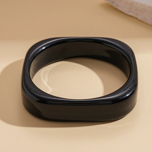 Macro shot of minimalist glossy black resin square-round bangle with high-shine finish