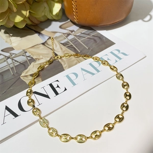 Detailed macro shot of a gold pig nose chain necklace on a lifestyle magazine background