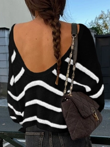 Detail of a women's black and white striped long sleeve knit sweater with an open V-back