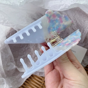 Détail d'une pince à cheveux en acétate avec nuages pastel et ressort métallique robuste