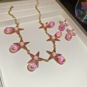 Detailed close-up of golden star jewelry set featuring marble beads and small pearls
