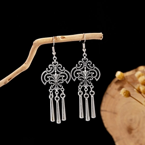 Detail view of retro silver tassel earrings with hollow patterns on wooden branch
