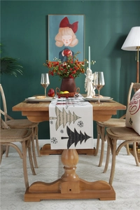 Detail of Christmas table runner with stylized tree and snowflake patterns on wood table