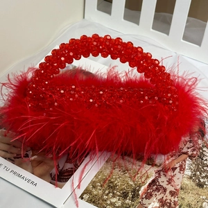 Close-up of red beaded handbag with soft ostrich feathers on a fashion magazine