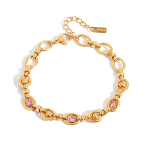 Detailed macro view of gold plated stainless steel bracelet with three pink zirconia stones