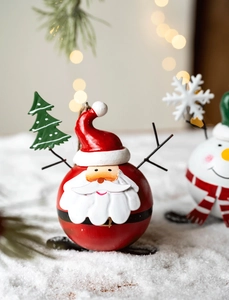Close-up of a spherical Santa skiing ornament with metal texture on a festive background