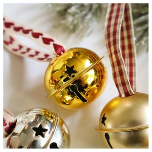 Macro shot of gold and silver Christmas bells with star cutouts and festive ribbons