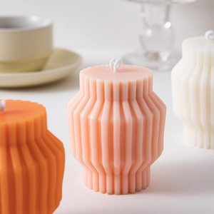Macro detail of geometric pillar scented candles in pink, orange, and white colors