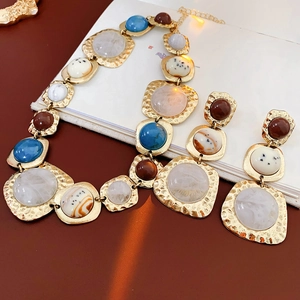 Artistic layout of vintage gold necklaces and earrings with colorful resin stones
