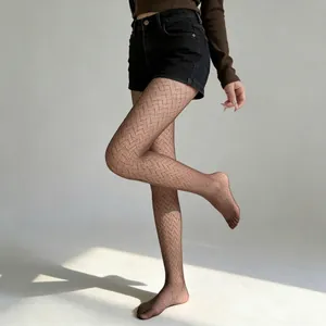 Detail of dark brown geometric chevron patterned tights shown on model in hard lighting