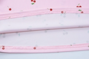 Gros plan sur maille rose côtelée avec imprimé cerise et détails de couture raffinés
