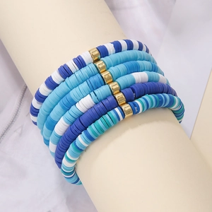 Detail view of 6-piece bohemian stackable bracelets with blue heishi beads and gold spacers