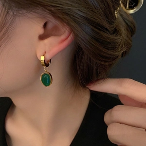 Elegant gold titanium steel earrings featuring oval emerald green drop stones on models