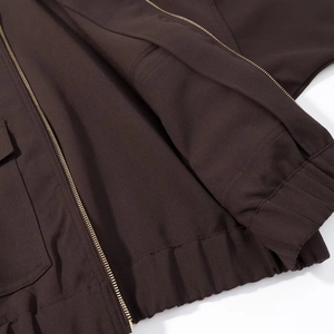 Detailed close-up of zipper, pocket stitching, and fabric texture on a dark brown jacket