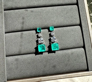Macro shot of 925 silver long drop earrings with emerald cut green synthetic stones