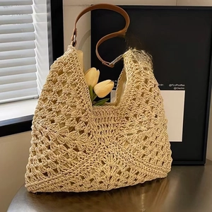 Dettaglio della borsa tote in paglia con trama a rete geometrica e manici in pelle marrone