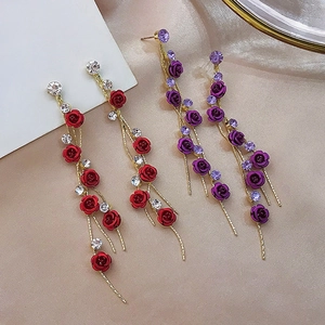 Detailed view of red and purple rose earrings with rhinestone tassels on beige silk