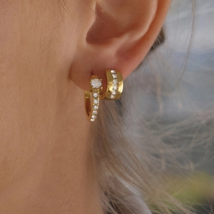 Gold stainless steel hoop earrings set with zircon stones worn on model ear