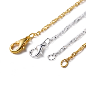 Macro detail of gold and silver DIY jewelry chains with lobster clasps and closed jump rings
