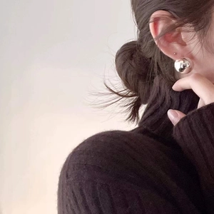 Minimalist S925 sterling silver sphere stud earrings worn by a model in profile view