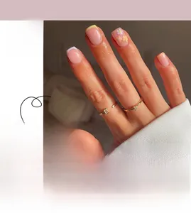 Détail de faux ongles French style avec fleurs jaunes et violettes sur base rose nude