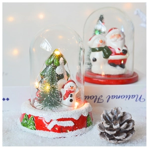 Close-up of LED Christmas glass dome with Santa and snowman on a snowy background