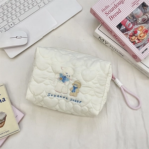 Close-up of white heart-quilted fabric with cute sheep embroidery and rope zipper pull
