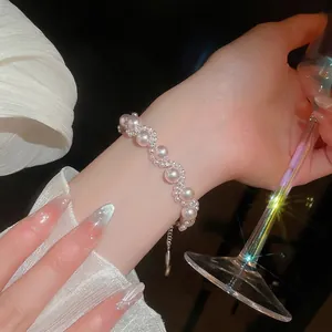 Elegant wrap pearl bracelet with rhinestone accents on woman's wrist with wine glass